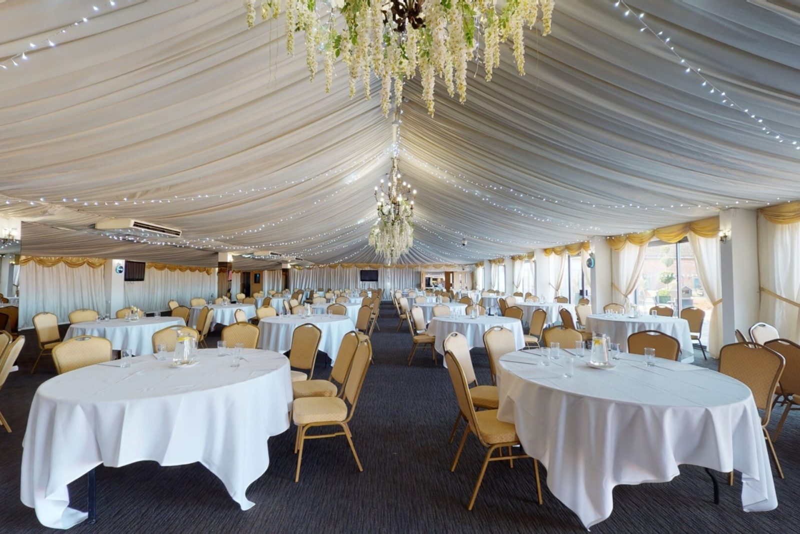 Elegant conference room setup with white tables and decorated ceiling
