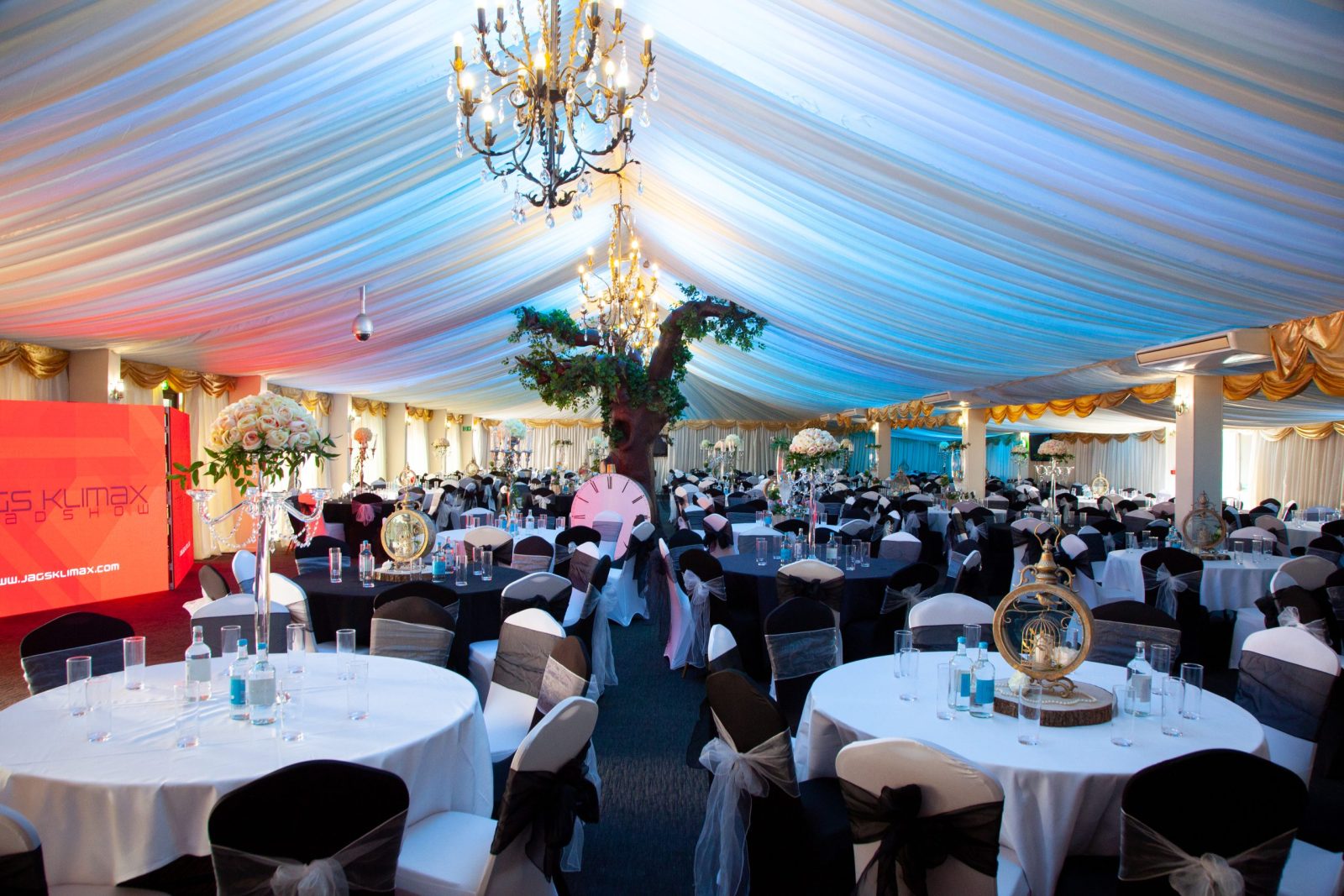 Decorated event venue with round tables and chandeliers