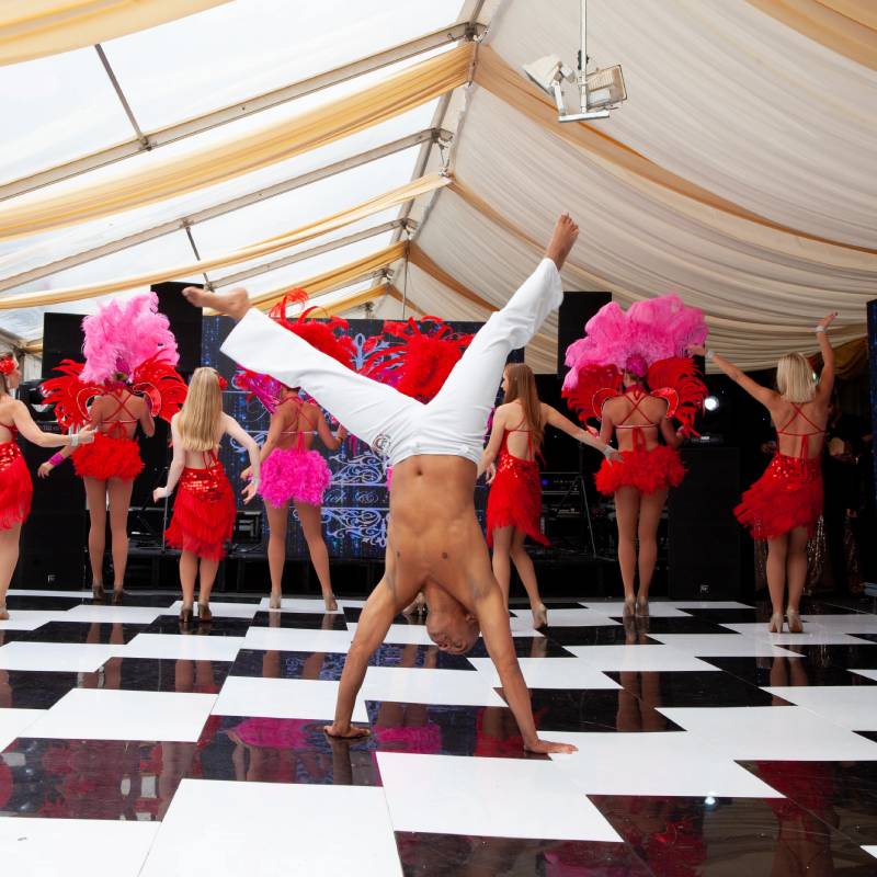 Performer doing handstand with dancers at event