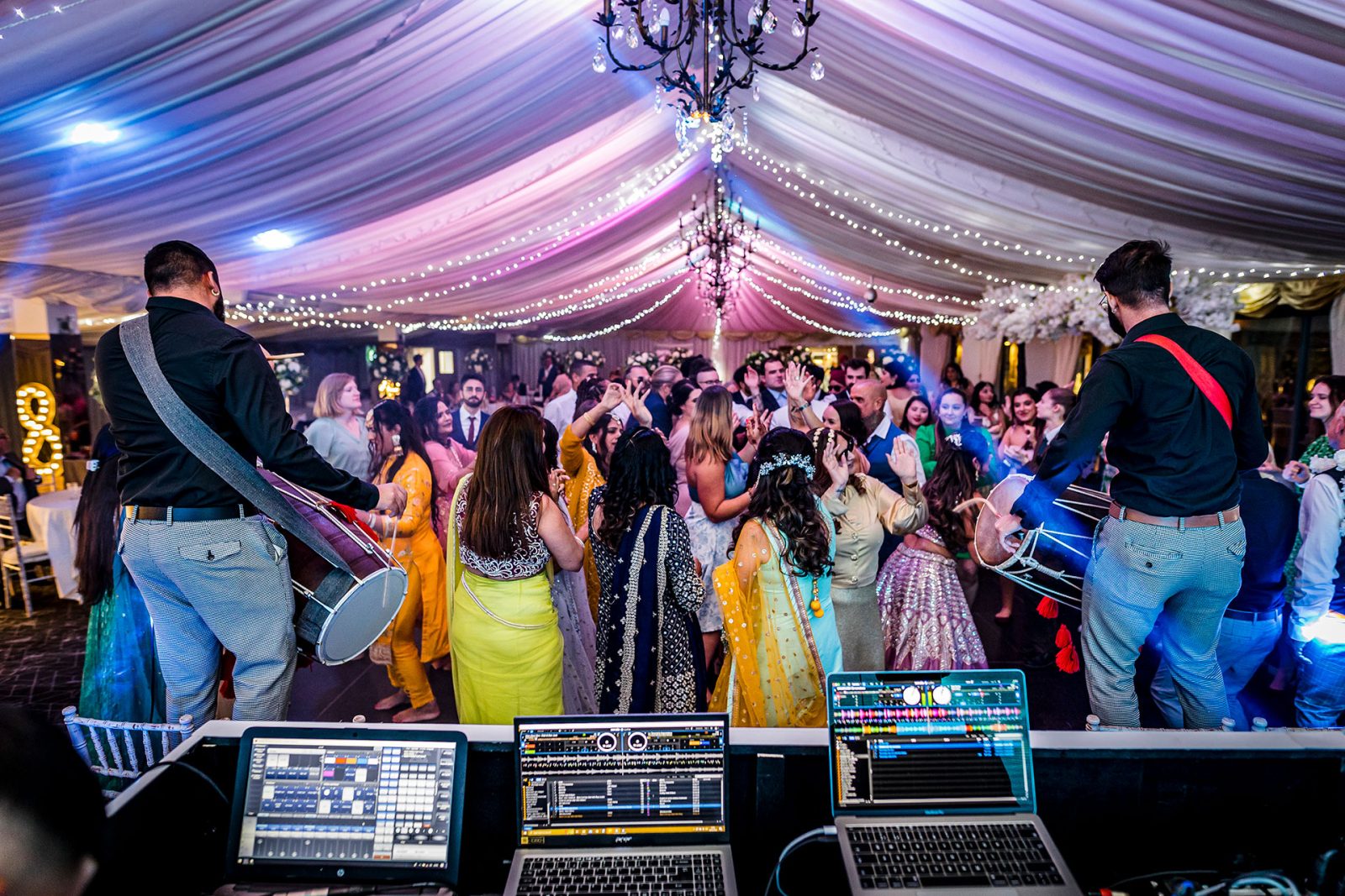 Wedding guests enjoying a lively dance floor with vibrant lighting