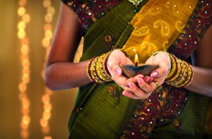 Close-up of hands holding a traditional diya, symbolizing festive occasions
